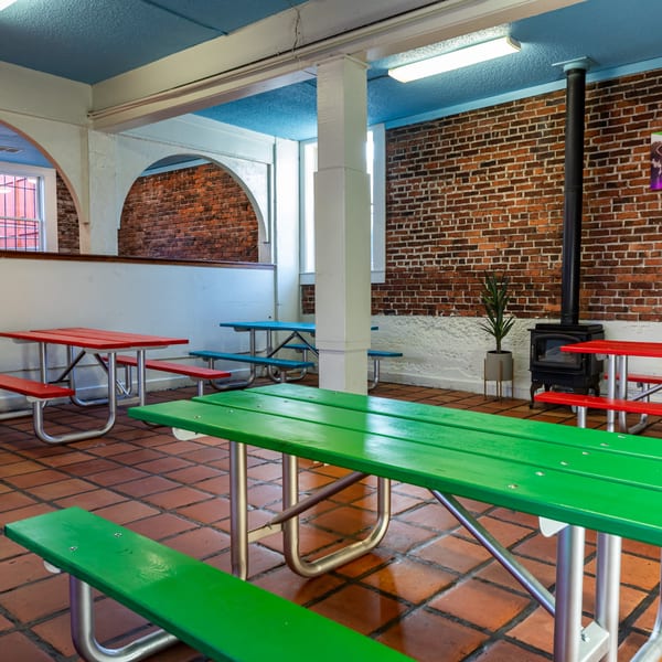 Gorditos' interior features colorful picnic tables, brick walls, a blue ceiling, and a wood-burning stove.