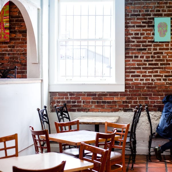 Gorditos' dining area with brick walls, wooden tables, and chairs, featuring a colorful skull artwork.