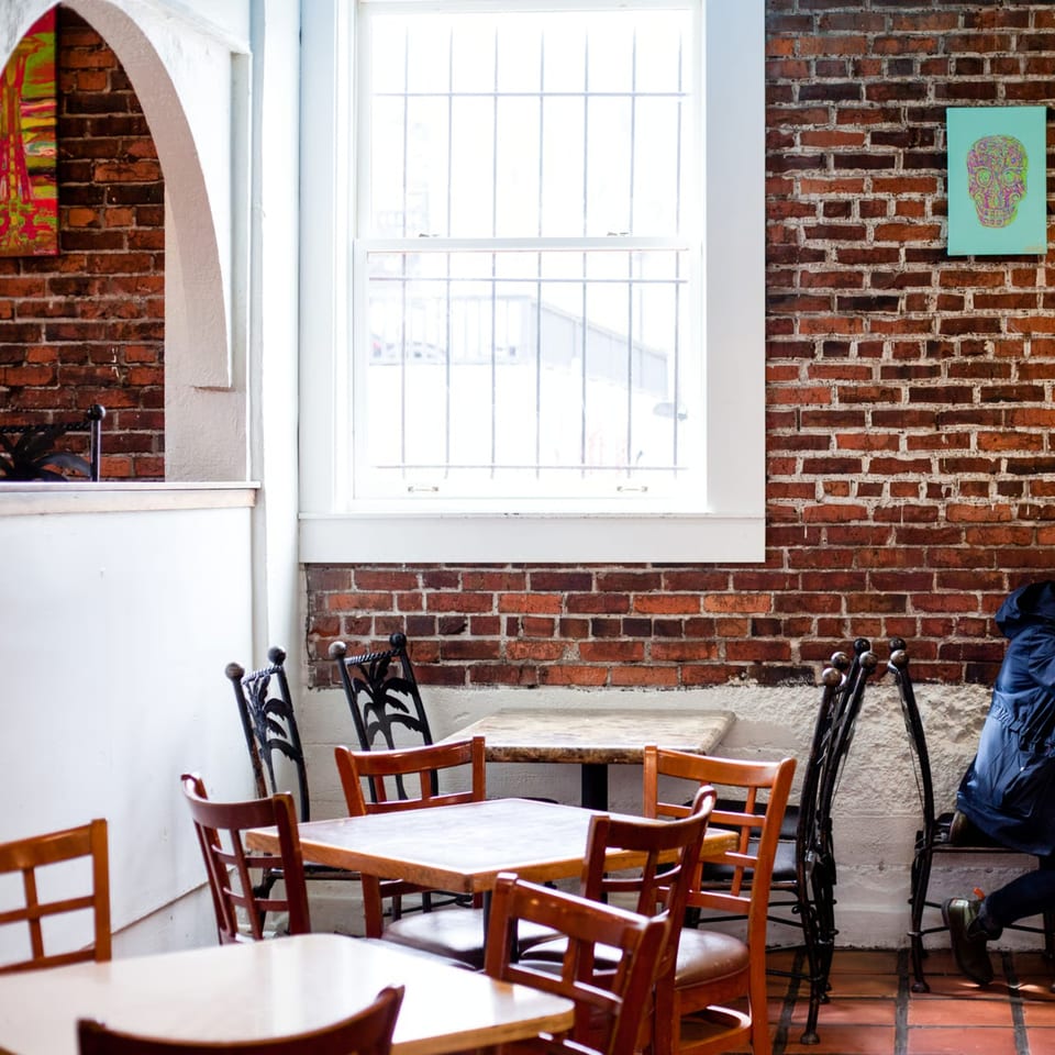 Gorditos' dining area with brick walls, wooden tables, and chairs, featuring a colorful skull artwork.