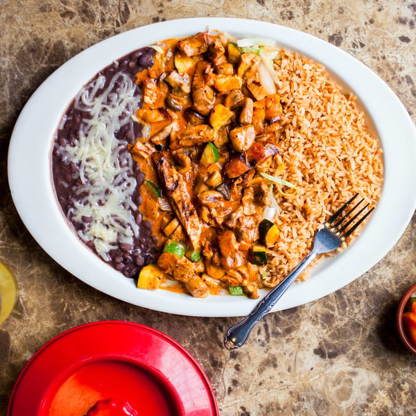 Gorditos' Mexican dish with chicken in red sauce, rice, and black beans with cheese.