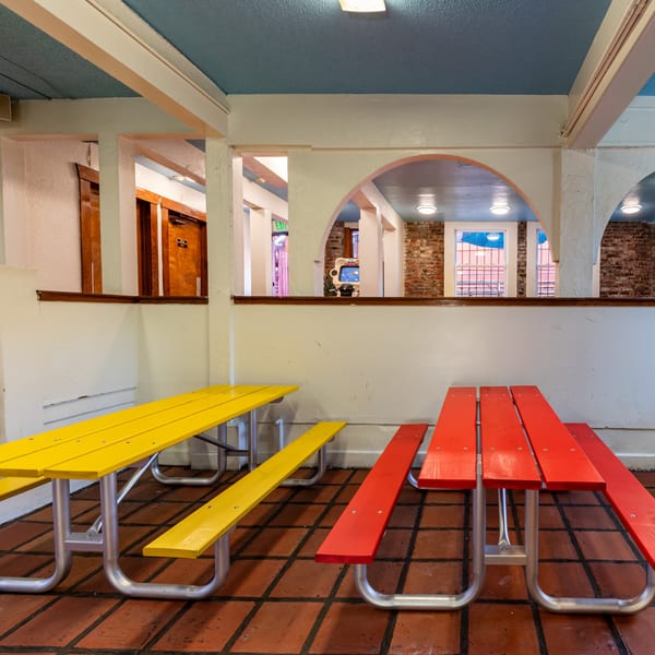 Gorditos' dining area with yellow and red picnic tables on a tiled floor, arched doorways, and brick walls.