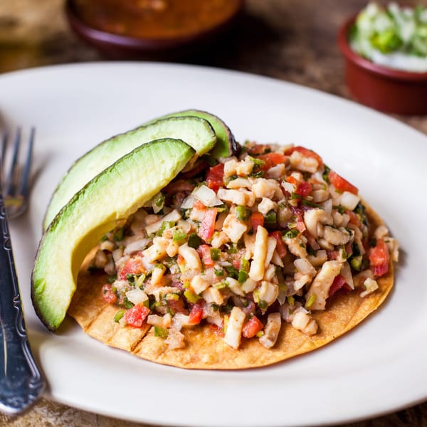 Gorditos' ceviche tostada with diced seafood, tomatoes, onions, and two avocado slices.