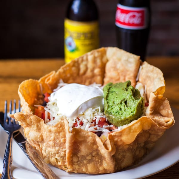 Gorditos' taco salad in a crispy shell with sour cream, guacamole, and two bottled drinks.