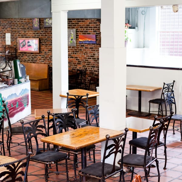 Interior of Gorditos restaurant with brick walls, tiled floors, and wrought iron chairs at wooden tables.